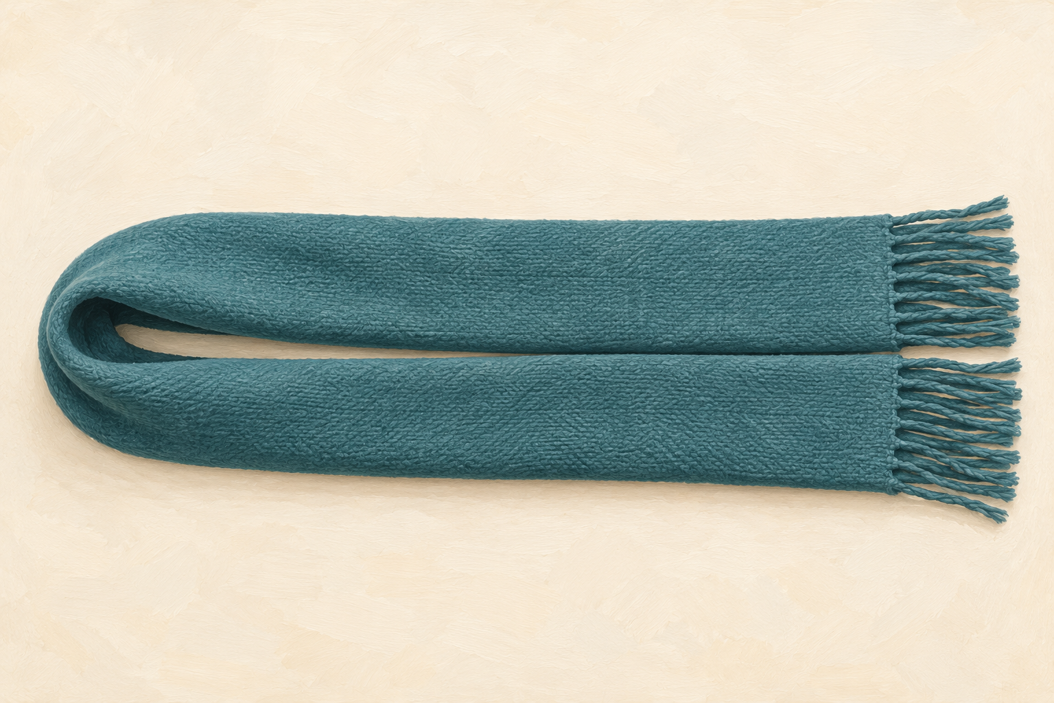 Rectangular teal scarf doubled back into a U, with the folded end on the left and both loose fringed ends aligned on the right.